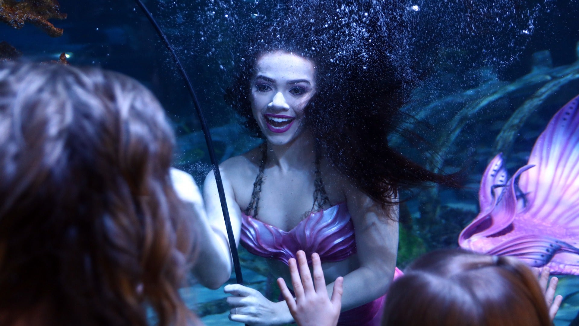 mermaid saying hi to kids in an aquarium